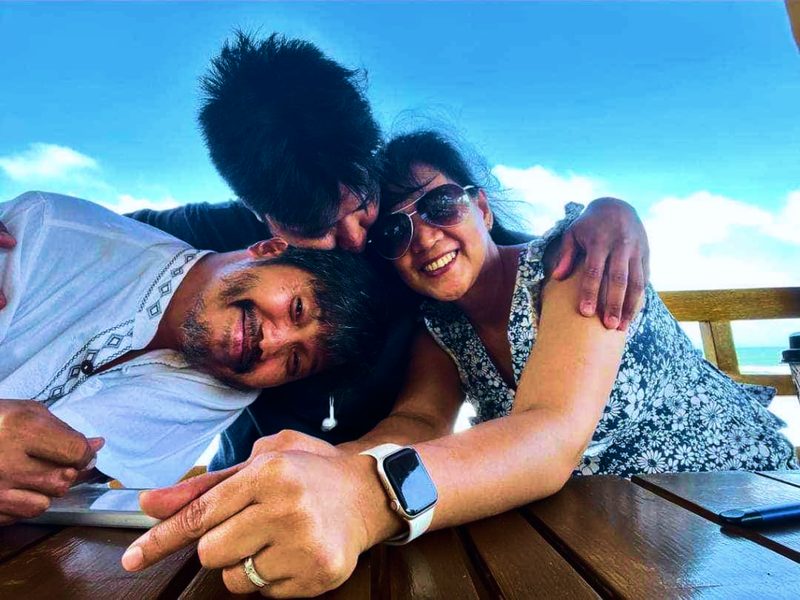 Three guests laughing together at a table by the sea